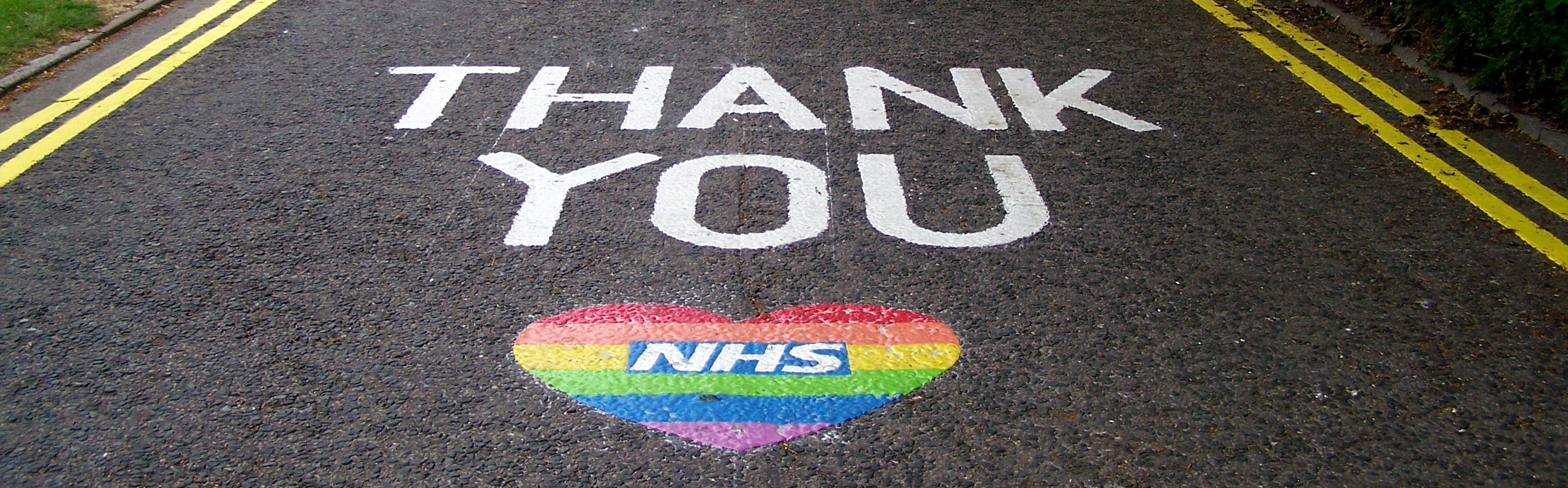 Thank you NHS started in during the COVID-19 pandemic when people in the UK posted messages of gratitude for their National Health Service (NHS), to acknowledge their crucial work. Picture adapted from an original CC-BY-SA picture of the NHS logo painted on road outside North Walsham Hospital in Norfolk, England by Whippetsgalore on Wikimedia Commons w.wiki/55Wc