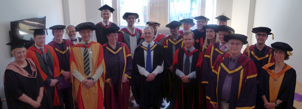 Wearing silly hats and even sillier frocks for a graduation ceremony in the Whitworth Building, Manchester in 2013. From left to right Alex Walker, Tim Morris, John Latham, Graham Gough, Yours Truly, Sean Bechhofer, Andrea Schalk, Gavin Brown, Toby Howard, Robert Stevens, Simon Harper, Barry Cheetham, Norman Paton, Bijan Parsia, Caroline Jay, Allan Ramsay, Darren Lunn, Nick Filer, Markel Vigo and Ulrike Sattler. Picture by Toby Howard. 🎓